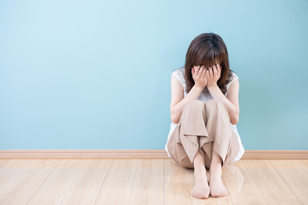 床に座り込み両手で顔を覆って泣いている女性